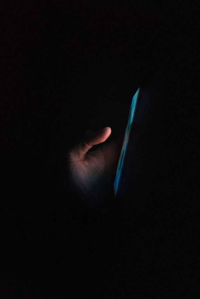 person holding blue light in dark room