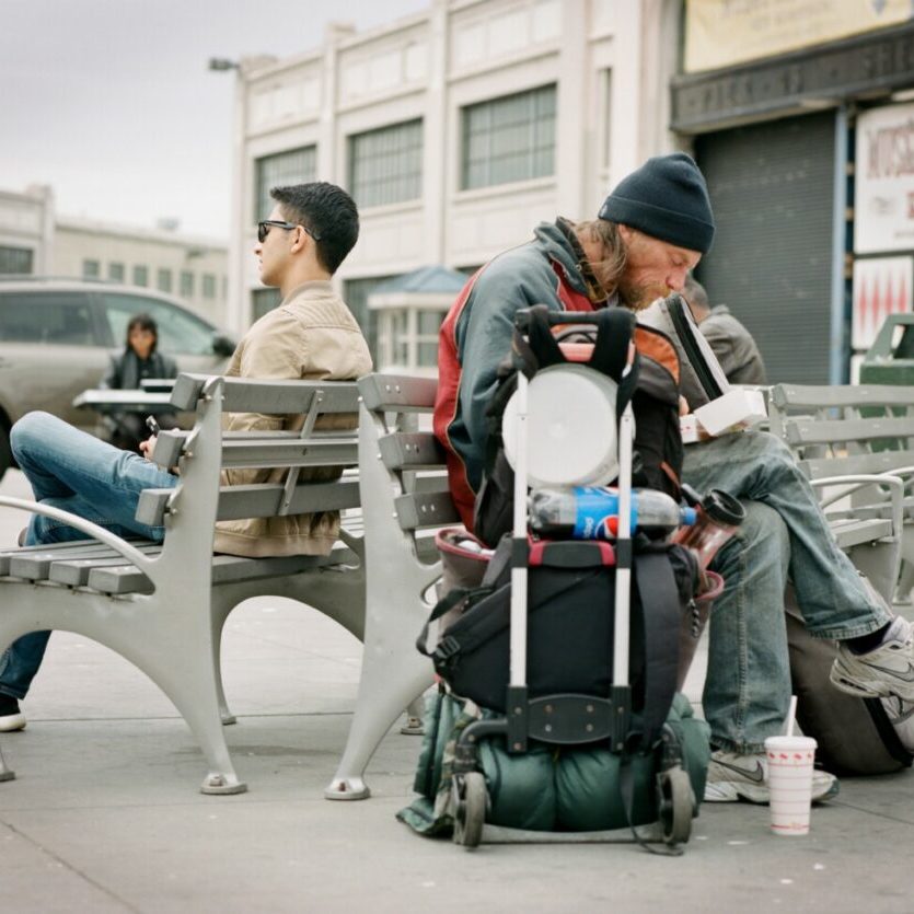 Photo par Benjamin Disinger man in black jacket and black pants carrying black and white backpack walking on sidewalk during