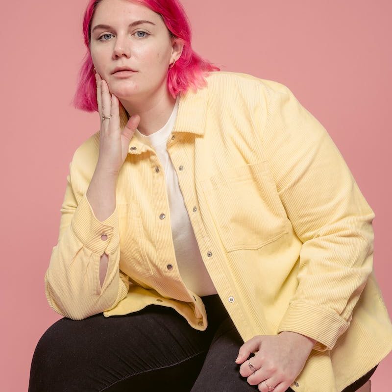 Serious woman touching face while sitting in studio