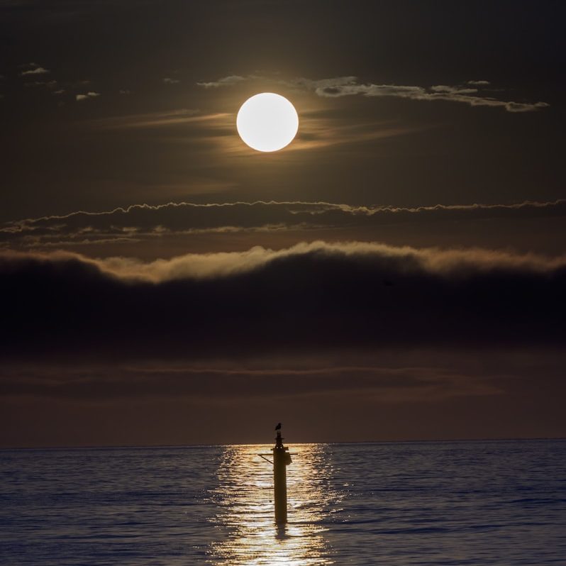 silhouette of tower under white clouds during night time