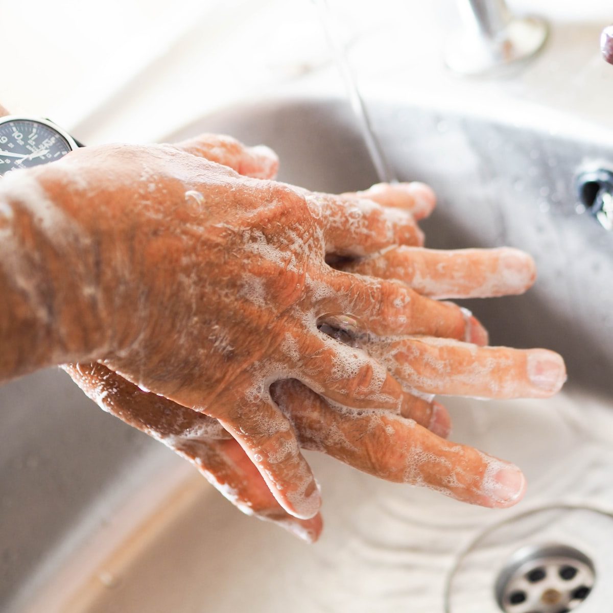 person washing hands on sink