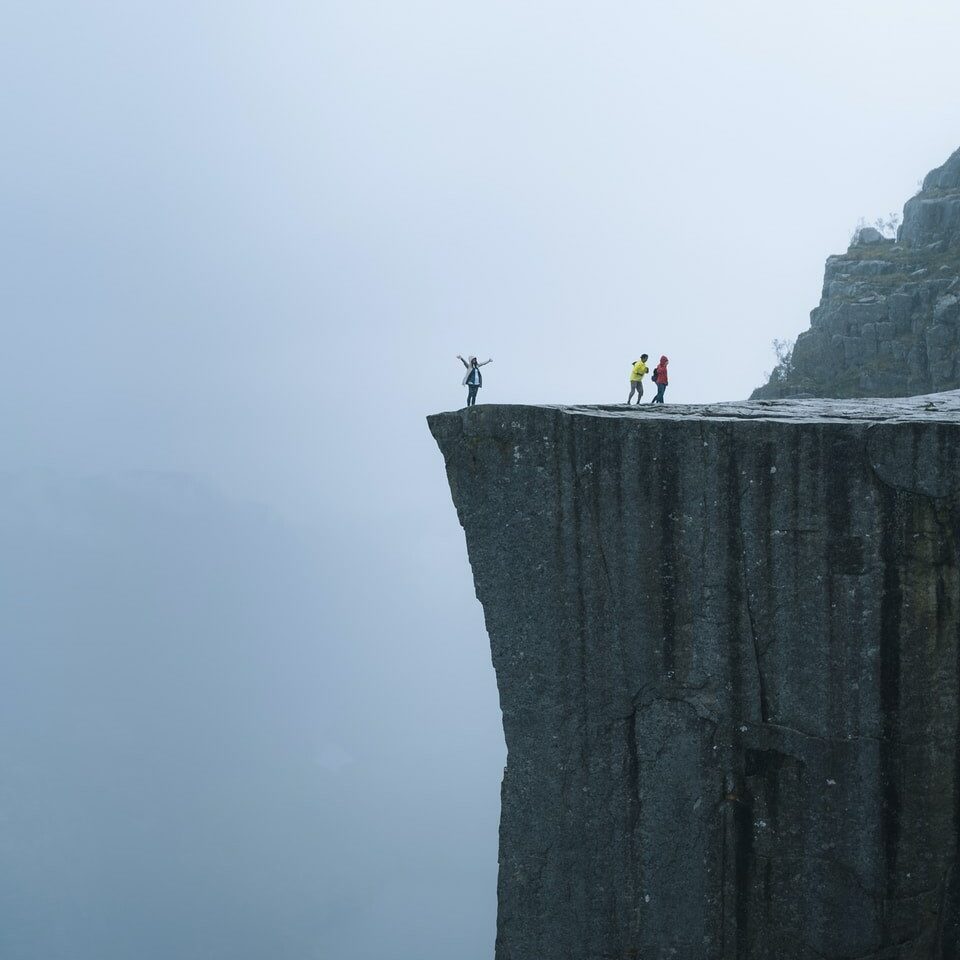 Photo par Valdemaras D. three persons standing near the edge of a cliff during day