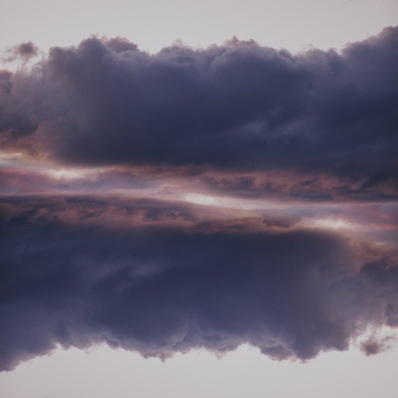 a plane flying through a cloudy blue sky