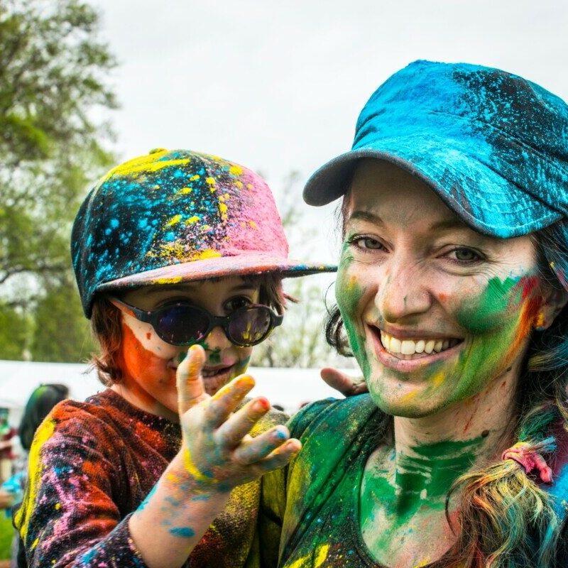 woman carrying child on color run