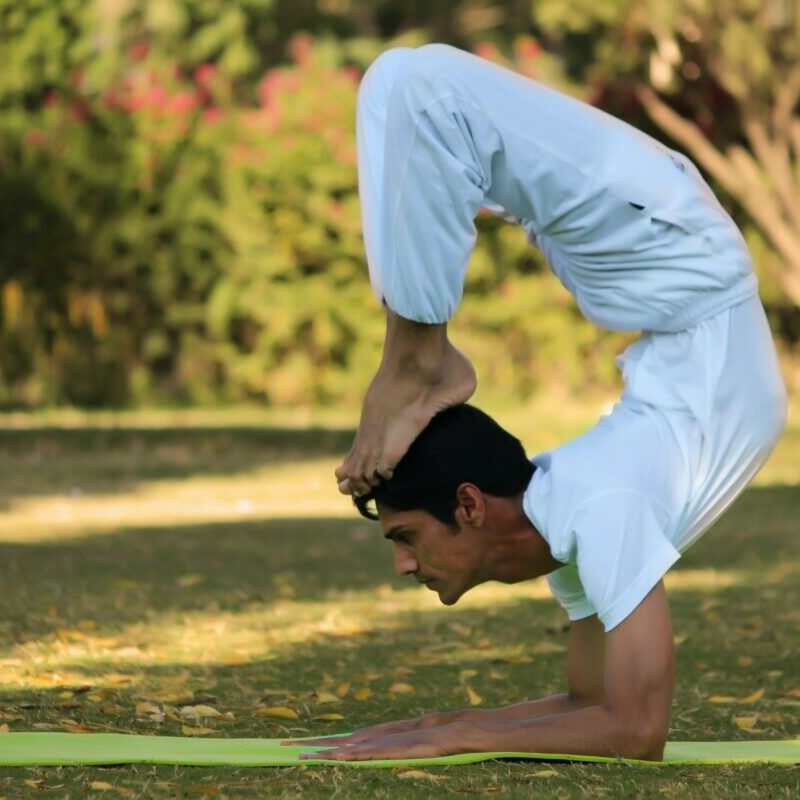 man acrobating on green pad during daytime