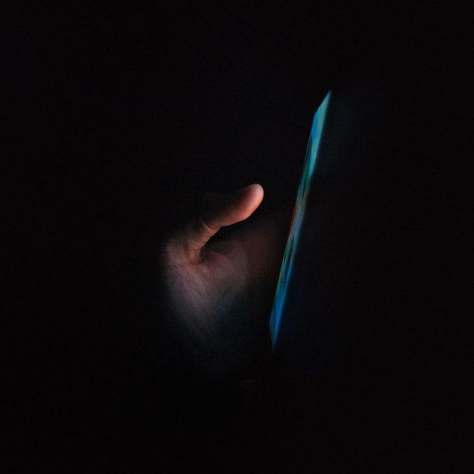 person holding blue light in dark room