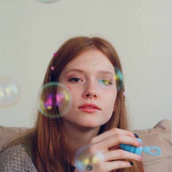 a woman sitting on a couch blowing bubbles